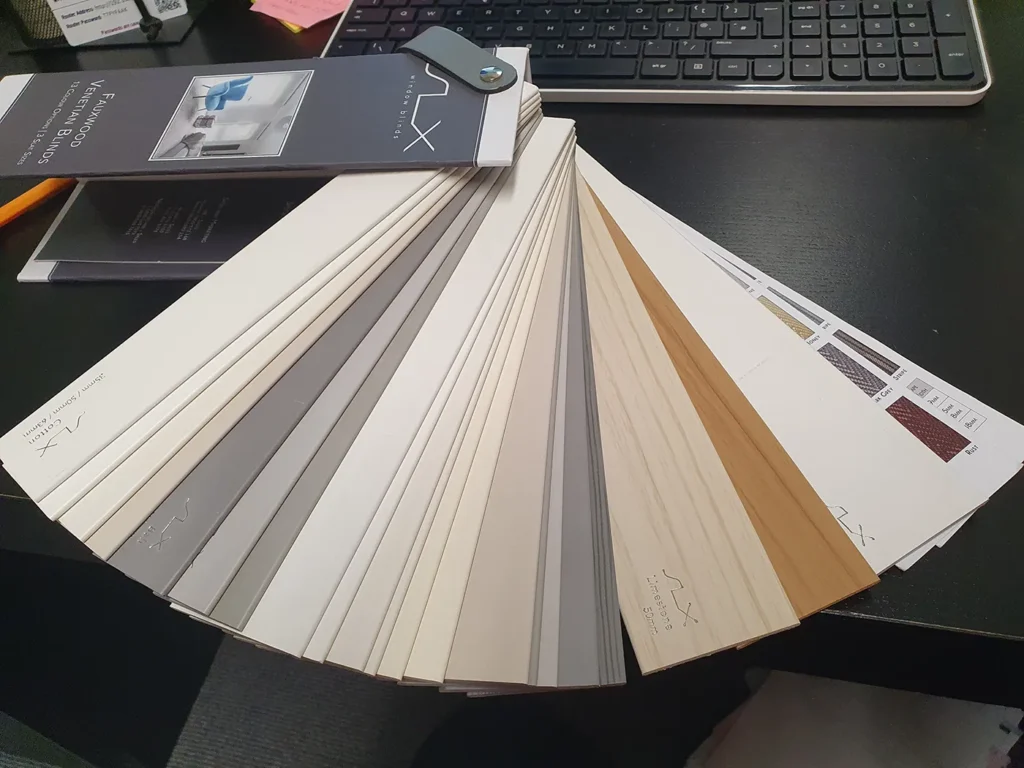 A fan of blind and shutter colour samples spread across a desk