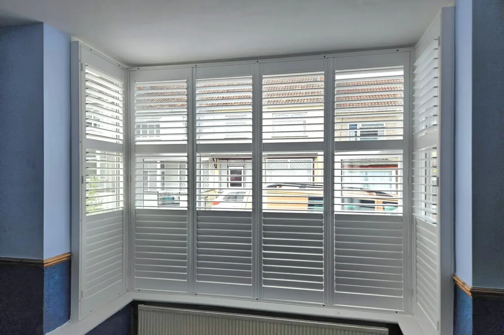 Tier-on-tier plantation shutters in a bay window with the top tier open