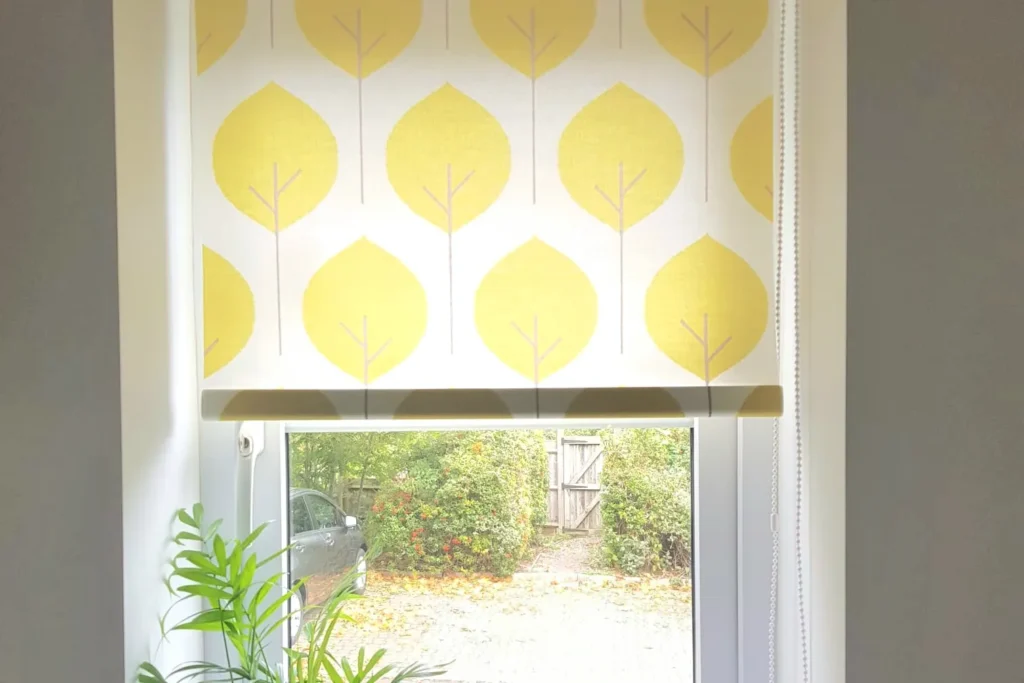A yellow patterned roller blind above a plant-filled window sill