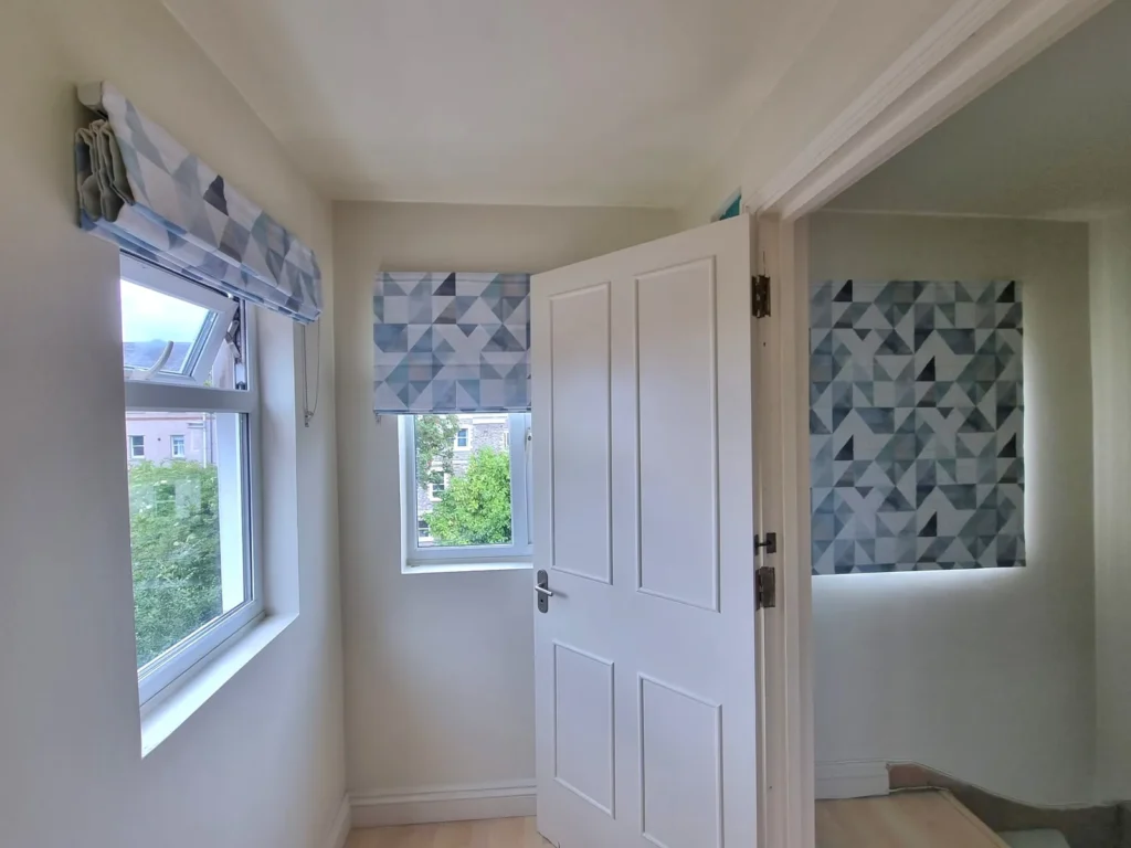 A Roman blind and coordinating printed blinds on adjacent landing windows