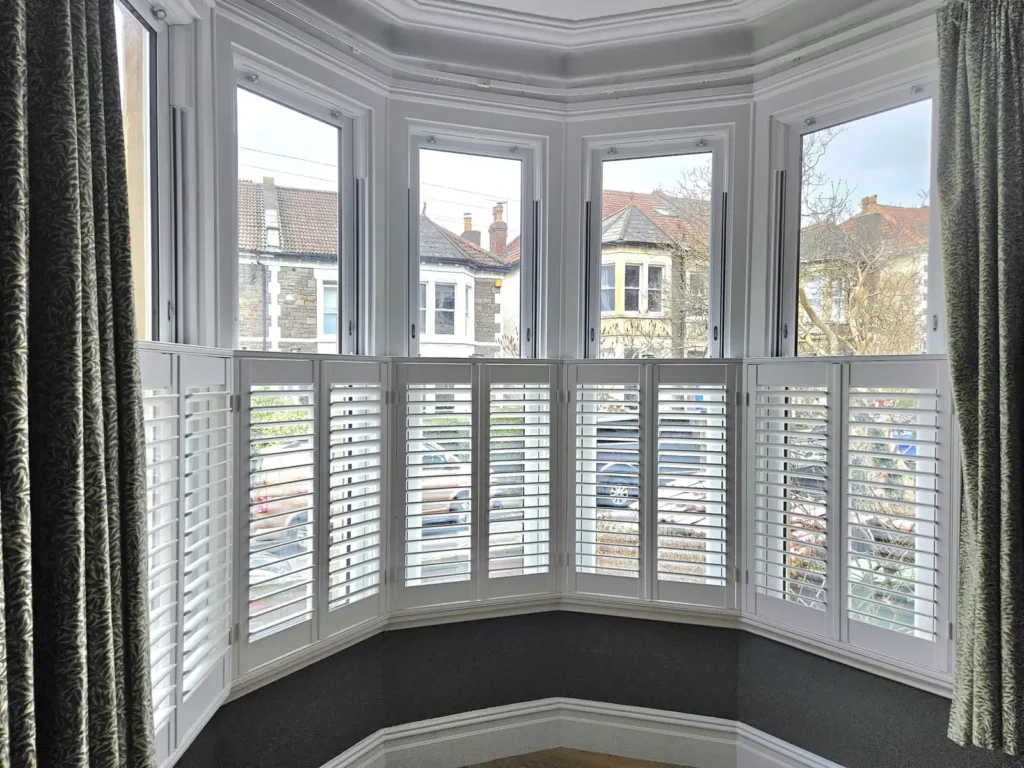 Plantation shutters on the lower half of a Victorian sash bay window