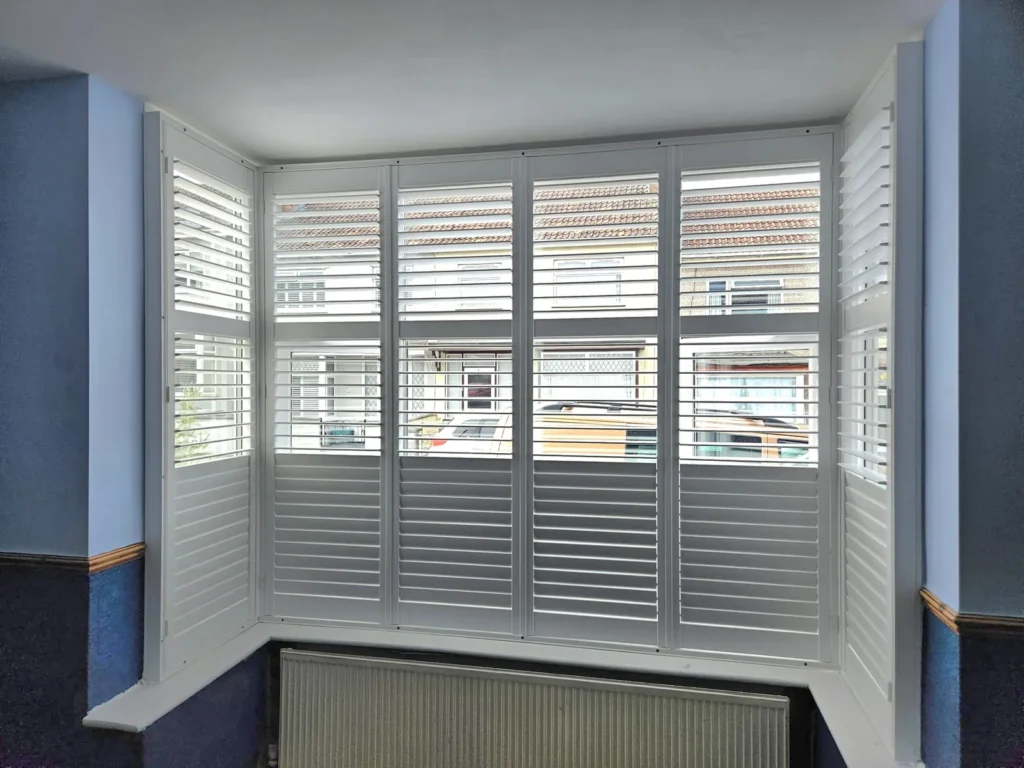 Tier-on-tier plantation shutters in a bay window with the top tier open
