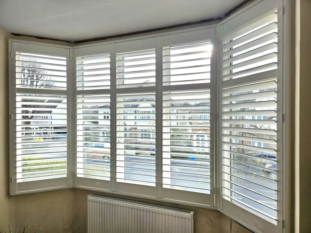 White plantation shutters following the angles of a three-panel bay window
