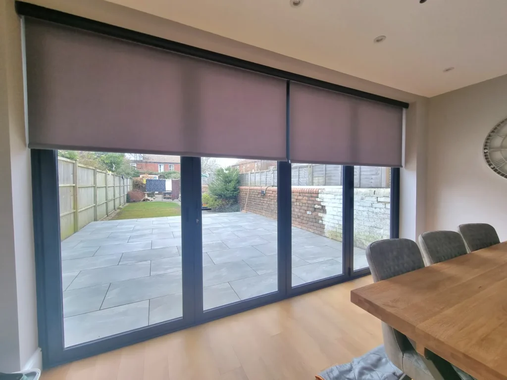 A wide taupe roller blind above patio doors in a Bristol dining room