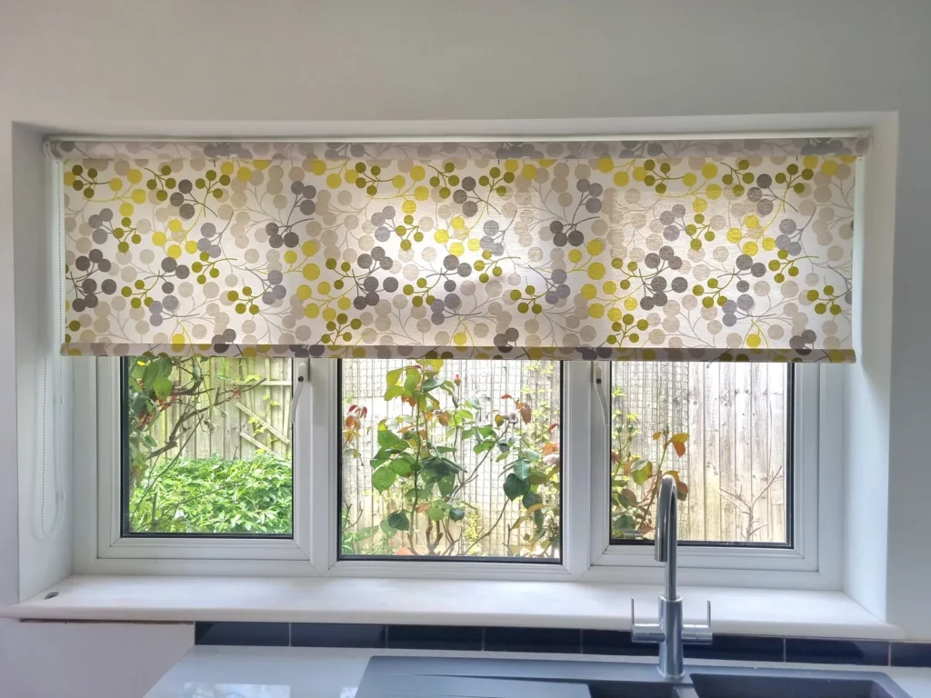 A patterned Roman blind above a kitchen window looking onto a Bristol garden