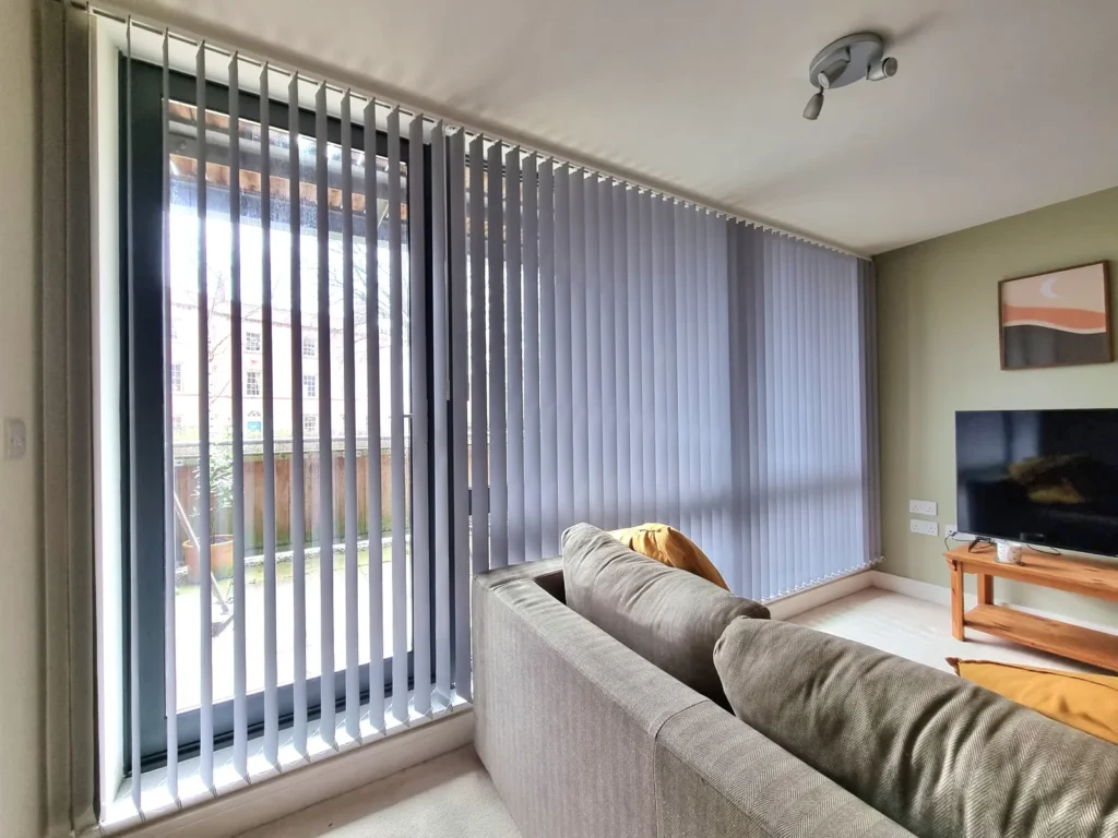 Grey vertical blinds across a full-height living room window in Bristol